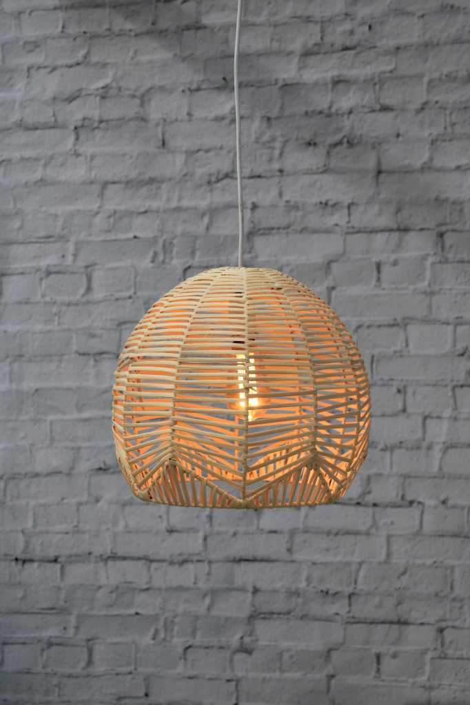 small rattan pendant against a white brick wall