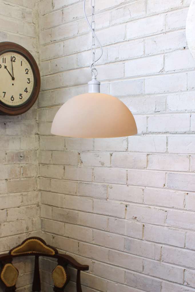 Small opal glass pendant with a white pendant chain against a white brick wall