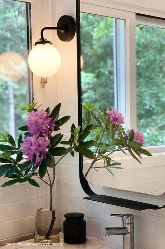 Glass Wall Light in a bathroom next to a mirror.