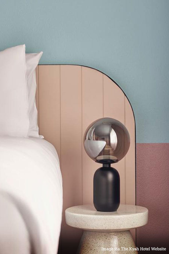 Black table lamp with glass ball shade in a hotel room.